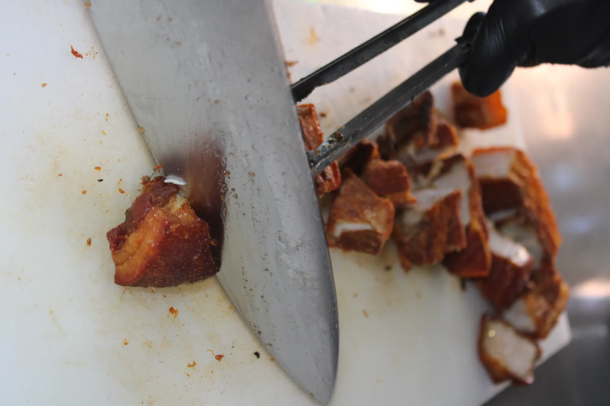 Chicharrón being cut and served into a foil bowl