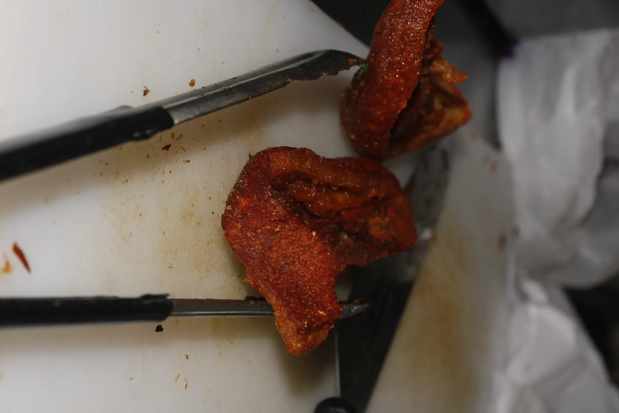 Fried pork belly being chopped on a cutting board, shot from above