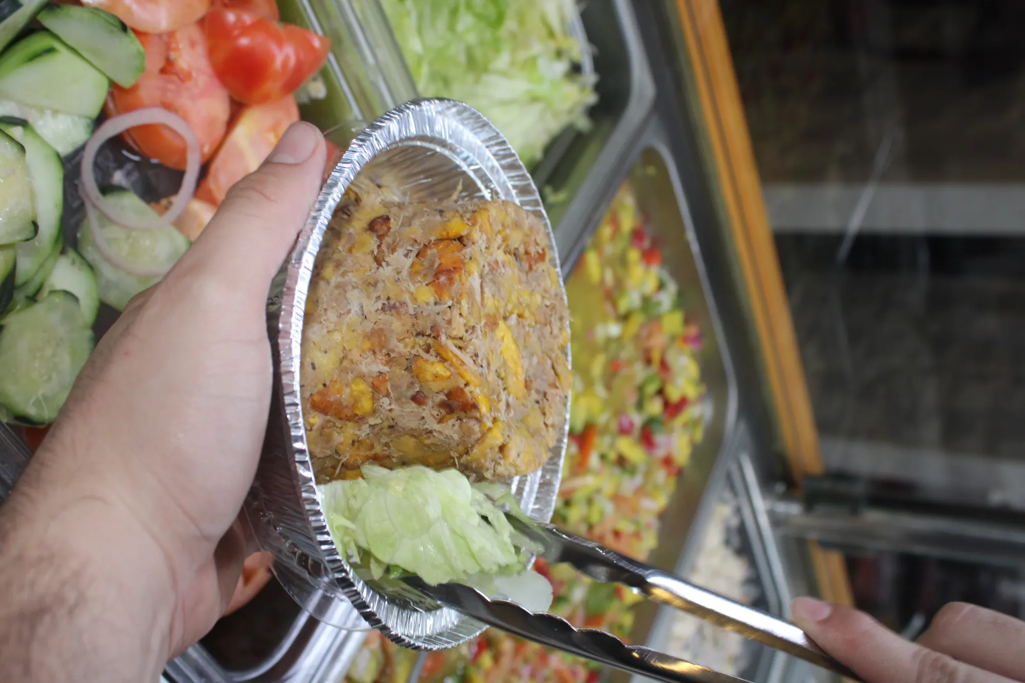 A mofongo dome being plated into a foil bowl at the steam table